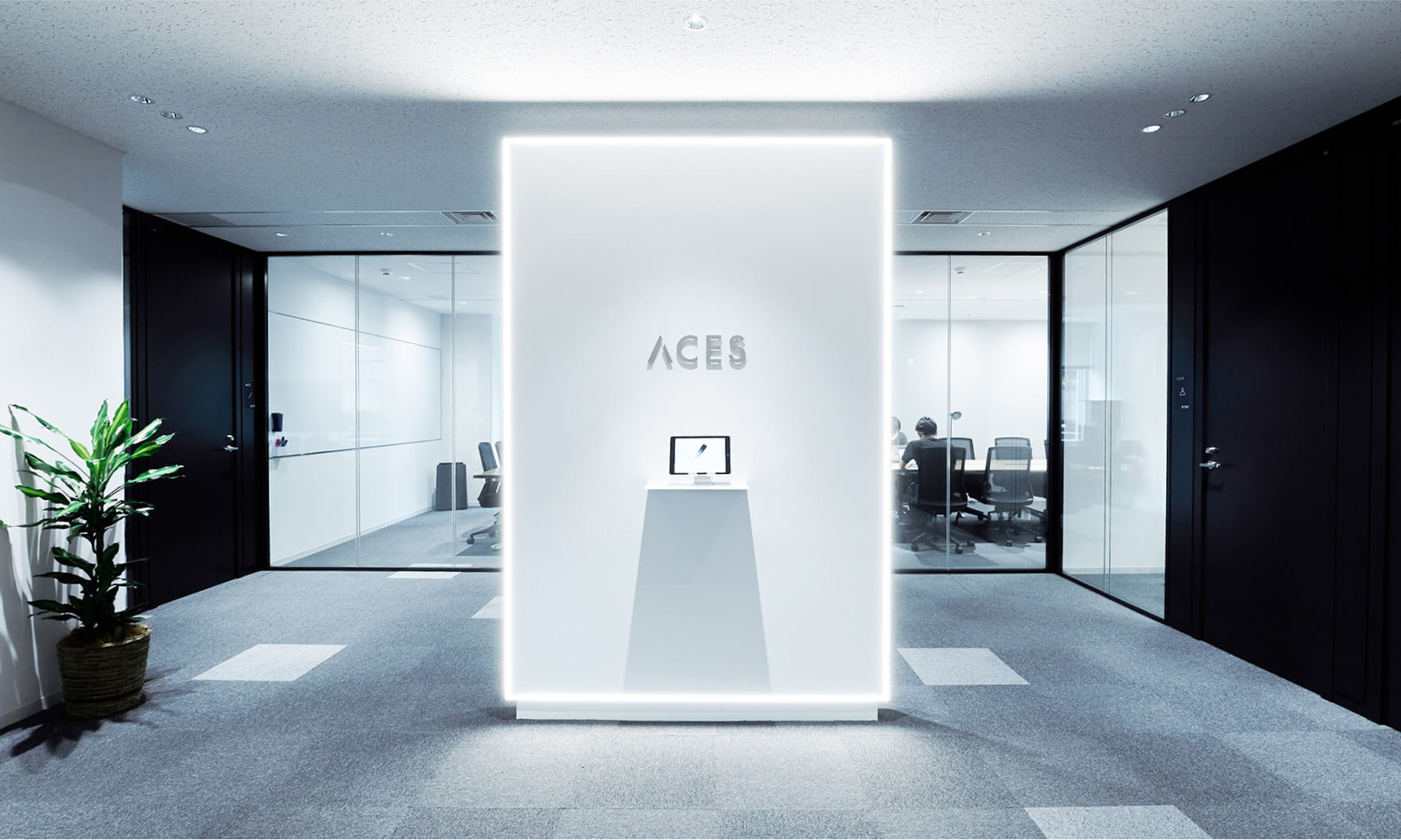 写真：近未来的な雰囲気のオフィスの入り口。ACESと書かれた看板が中央に見える。